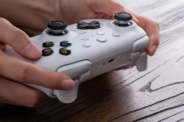 木製の机の上に白いゲームコントローラーを持っている人の写真